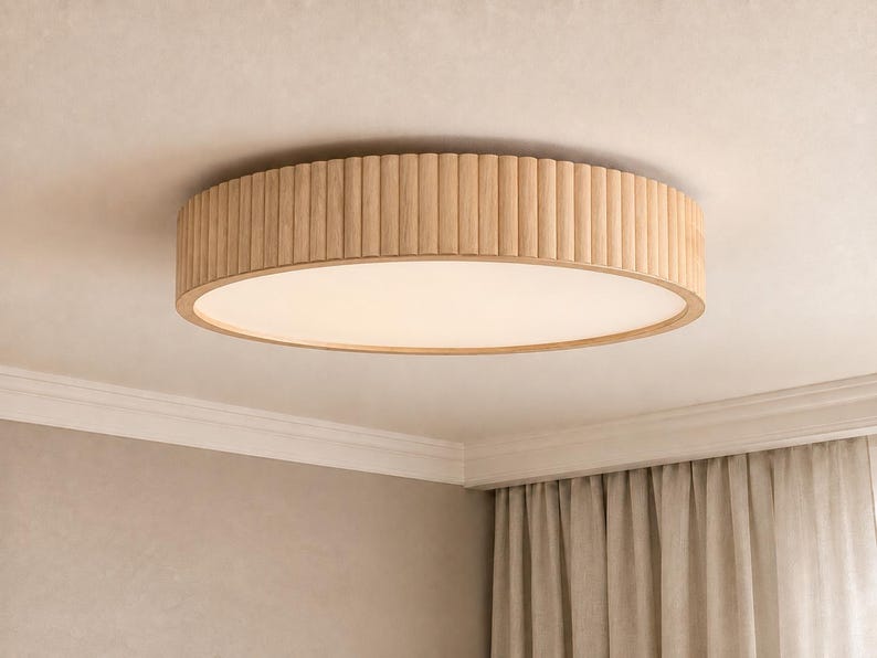 May include: A round flush mount ceiling light fixture featuring a light-toned wood frame with a vertical fluted or ribbed texture around the exterior edge and a flat, circular white diffuser panel centered on the underside of the fixture.
