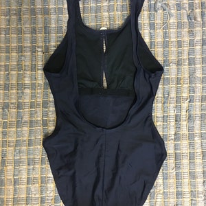 May include: A black one-piece swimsuit with a racerback style and a keyhole opening in the back.