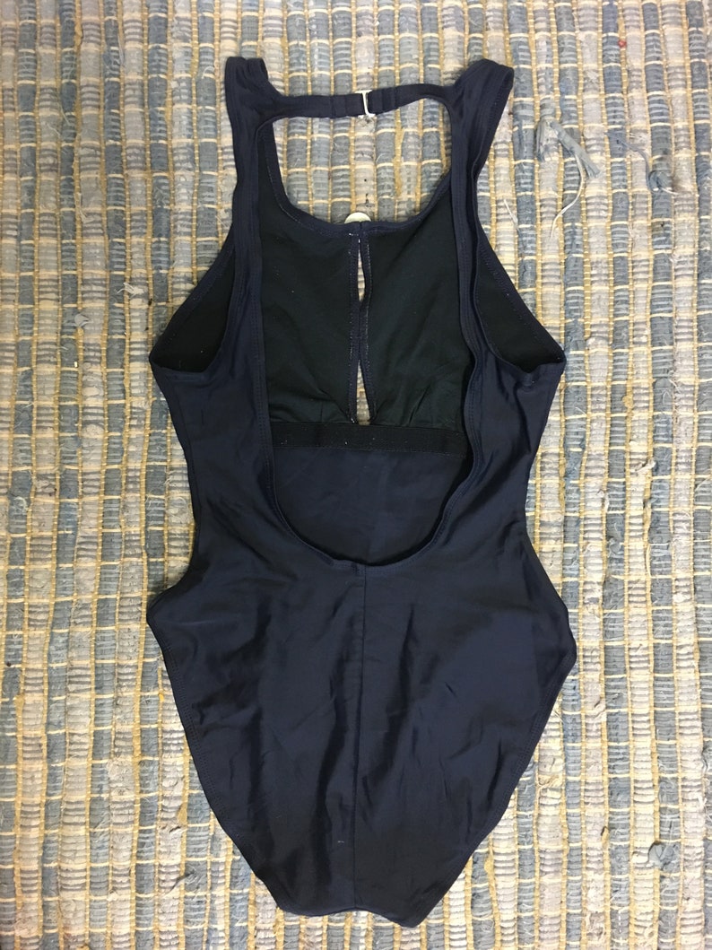 May include: A black one-piece swimsuit with a racerback style and a keyhole opening in the back.