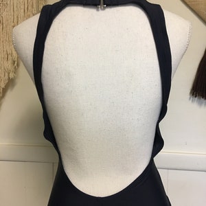 May include: A black swimsuit with a low back and a halter neck strap.