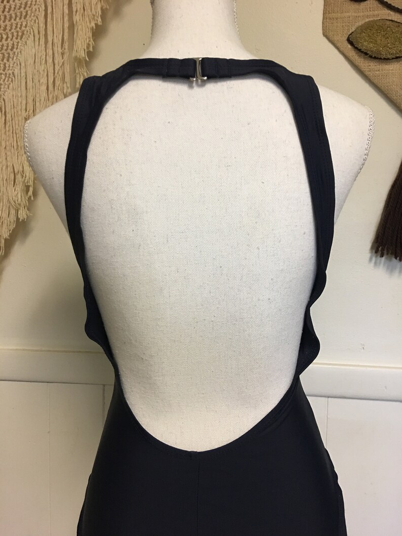 May include: A black swimsuit with a low back and a halter neck strap.