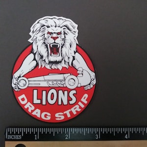 May include: A red and white circular sticker with a roaring lion illustration and the text "Lions Drag Strip".