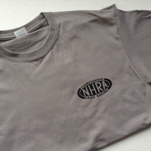 May include: Gray t-shirt with a black oval logo that says "NHRA Championship Drag Racing".