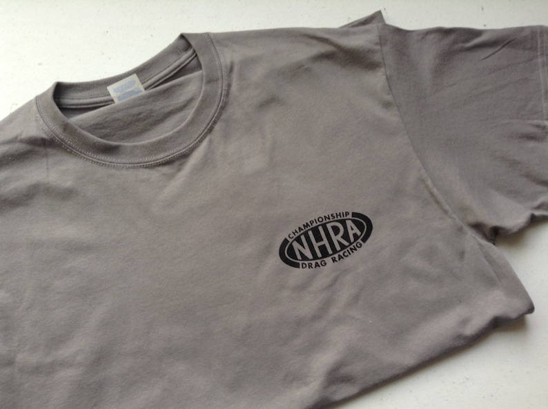 May include: Gray t-shirt with a black oval logo that says "NHRA Championship Drag Racing".