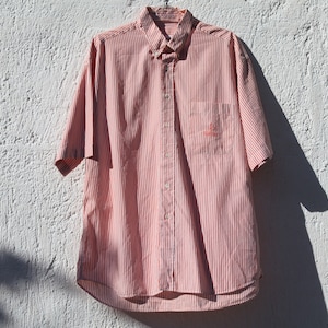 May include: A pink and white striped short-sleeved button-down shirt.