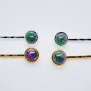 May include: Set of four gold and silver hair clips with green and pink gemstone accents.