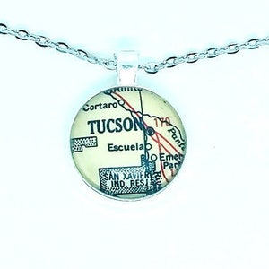 May include: A silver chain necklace with a round pendant featuring a vintage map of Tucson, Arizona. The map shows the city's streets and landmarks, including the words "TUCSON" and "Escuela".