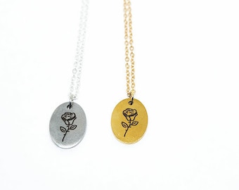 May include: Two delicate necklaces with rose pendants. One necklace has a silver pendant with a black rose design, and the other has a gold pendant with a black rose design.