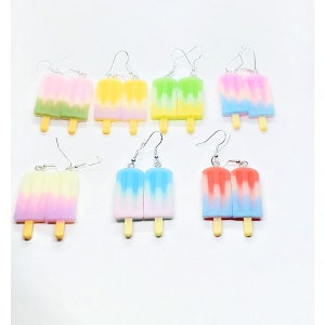 Op de afbeelding: Een set van 6 paar kleurrijke ijslolly oorhangers. Elk paar heeft een andere kleurencombinatie van roze, geel, groen, blauw en rood.