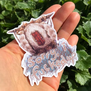 May include: A sticker with a fantasy creature illustration, featuring a furry body, horns, and a red gem. The sticker includes the text "Sorry, I fucked up" in a handwritten style.