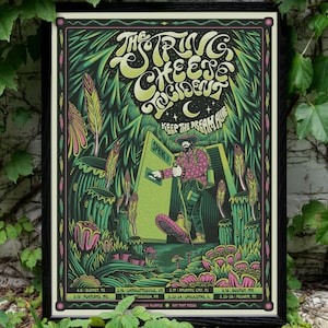May include: A framed poster with a black border featuring a psychedelic design. The poster has a dark green background with neon green, pink, and yellow accents. The text "The String Cheese Incident" is at the top. A figure stands in a doorway. Dates and locations are listed at the bottom.