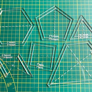 Op de afbeelding: Een set transparante kunststof sjablonen voor quilten of knutselen. De sjablonen omvatten een 5 cm zeshoek, een 5 cm ruit, een 5 cm vierkant, een 5 cm vijfhoek en een 5 cm 60 graden driehoek.