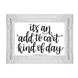 May include: White framed print with black text that reads "it's an "add to cart" kind of day" and the website address "CristinApril.com".