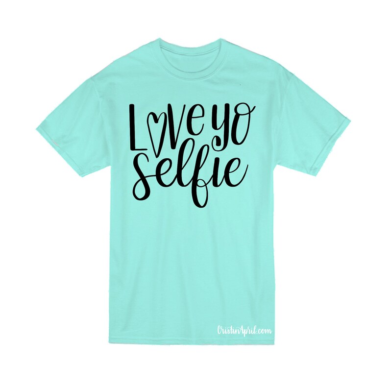 May include: A turquoise blue t-shirt with the text "Love yo selfie" in black lettering with a small heart replacing the "o".