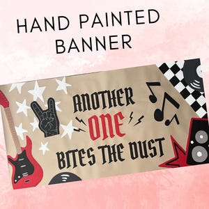 May include: Hand-painted banner with a rock and roll theme. The banner features a red guitar, a hand making the rock on gesture, white stars, musical notes, and the phrase "Another One Bites the Dust."