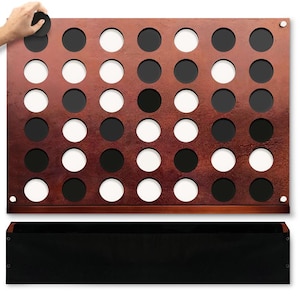 May include: A copper-colored metal game board with black and white circles. The board is mounted on a wooden frame. A black disc is being placed on the board.