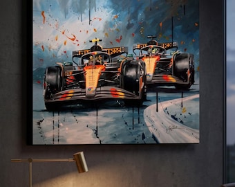 May include: A framed canvas art print featuring two Formula 1 race cars in action. The cars are orange and black, racing on a track with a blue and white background. The artwork has a dynamic, painterly style with splashes of color.