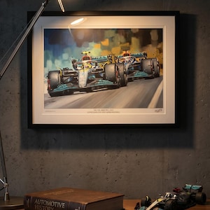 May include: Framed artwork depicting two Formula 1 cars racing, with the text "Silver Arrows 2021 Lewis Hamilton and George Russell". A model race car and a book titled "Automotive History" are on a wooden surface.
