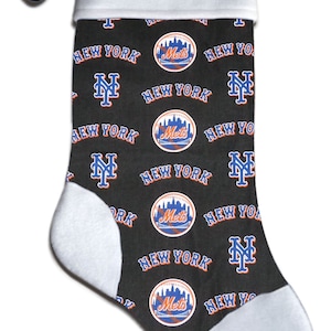 May include: A black Christmas stocking with a white cuff and toe. The stocking is patterned with the New York Mets logo and the words "New York". The name "Brian" is printed on the cuff.