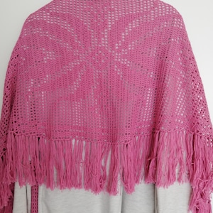 May include: A pink crocheted shawl with a delicate openwork pattern and a fringe border.
