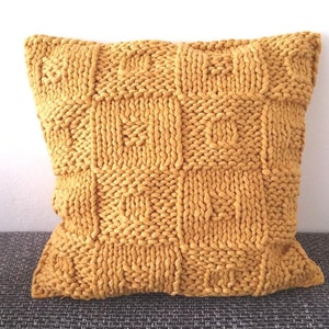 May include: A mustard yellow knitted throw pillow with a square pattern.