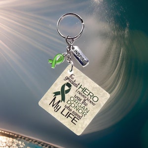 Peut inclure: Un porte-clés avec un ruban vert et une étiquette carrée sur laquelle est inscrit "Le plus grand HÉROS que je n'ai jamais connu était le DONNEUR D'ORGANES qui a sauvé Ma VIE". Le porte-clés comporte également un petit charme sur lequel est inscrit "INSPIRE".