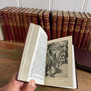 May include: A vintage, brown leather-bound book with gold accents and a black and white illustration of people in a forest. The book is open to a page with the text "He staggered back two or three paces. Page 175."