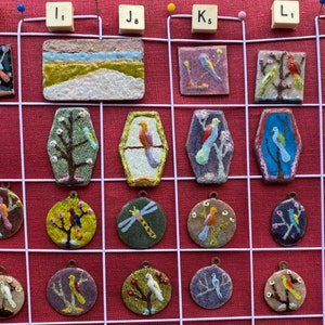 Può includere: Una griglia di 16 piccole piastrelle in ceramica con vari disegni di uccelli e natura. Le piastrelle sono disposte in quattro file di quattro. Ogni piastrella ha un design diverso, tra cui uccelli, alberi, fiori e una libellula. Le piastrelle sono tutte dipinte in colori vivaci, tra cui blu, verde, giallo, rosso e bianco.