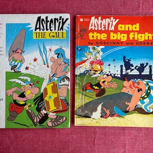 May include: Two vintage Asterix comic books. The book on the left is titled "Asterix the Gaul" and the book on the right is titled "Asterix and the Big Fight". Both books feature colorful illustrations of the characters.