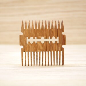 May include: A wooden comb with a razor blade design. The comb has a brown wood grain and is made of natural wood.
