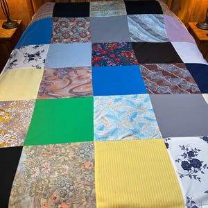 May include: A patchwork quilt made from various fabric scraps in different colors and patterns, including floral, geometric, and abstract designs.