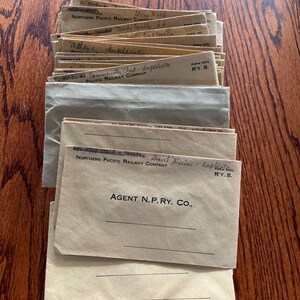 May include: A stack of vintage envelopes with handwritten text, including "Stony Wald", "NORTHERN PACIFIC RAILWAY COMPANY", "Brent Mission - Duplicate", and "AGENT, N.P. RY. CO.".