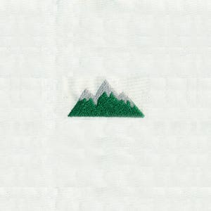 May include: An embroidered mountain design in green and white on a white fabric background.