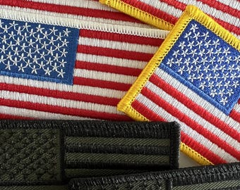 May include: Four embroidered American flag patches, two with yellow borders and two with black borders. The patches are arranged in a stack.