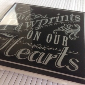 May include: Black and white sign with the text "Dogs leave paw prints on our hearts".