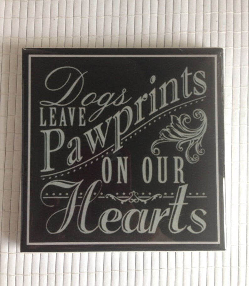 May include: Black and white sign with the text "Dogs leave paw prints on our hearts".