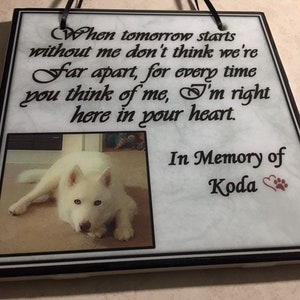 K&ouml;nnte beinhalten: Wei&szlig;e Keramikfliese mit schwarzem Rand und einem Foto eines wei&szlig;en Hundes. Die Fliese tr&auml;gt eine schwarze Inschrift mit dem Text "Wenn morgen ohne mich beginnt, denk nicht, dass wir weit entfernt sind, denn jedes Mal, wenn du an mich denkst, bin ich genau hier in deinem Herzen." Unter der Inschrift steht "In Gedenken an Koda" mit einem roten Herzen und einem Pfotenabdruck.