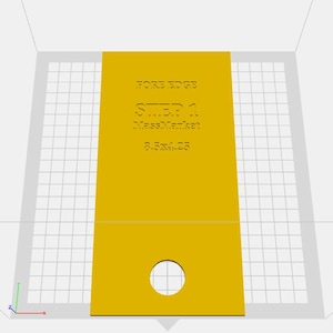 May include: A yellow rectangular object with the text "FORE EDGE STEP 1 MassMarket 3.5x4.25". The object has a circular hole near the bottom and is set against a grid background.