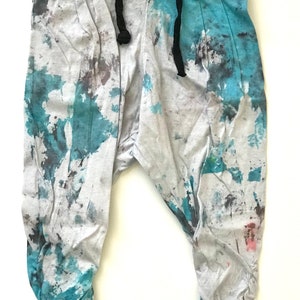 May include: Grey sweatpants with a blue and grey tie-dye pattern. The sweatpants have a drawstring waist and a relaxed fit.