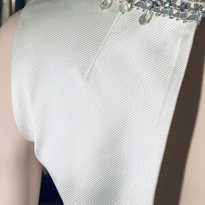 May include: White sleeveless dress with a beaded neckline. The beads are silver and clear.