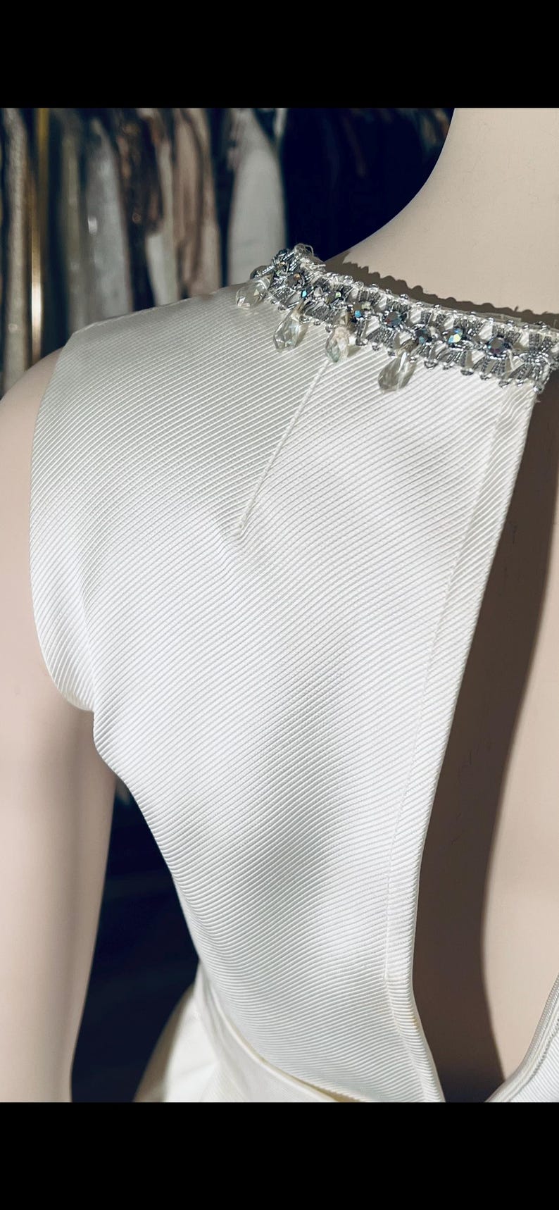 May include: White sleeveless dress with a beaded neckline. The beads are silver and clear.