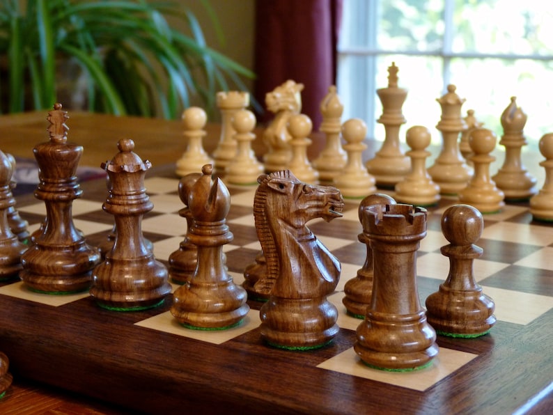 Walnut and maple chess board set up on a table, with beautifully carved wooden chess pieces.