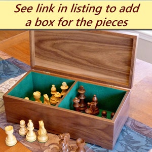 Walnut box for chess pieces is shown with the lid open revealing two compartments, one for light pieces, one for dark. Compartments are lined with green felt flocking. The box is available separately.