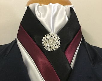 May include: A white, black, and burgundy satin stock tie with a silver rhinestone brooch.