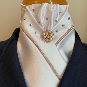 May include: White satin stock tie with a rose gold trim and a pearl and rhinestone brooch.