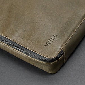 May include: A green leather zippered pouch with the name "WILL" embossed on the front.