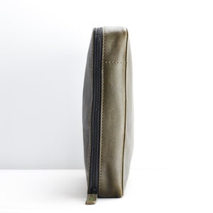 May include: A green leather zippered pouch with a black zipper.