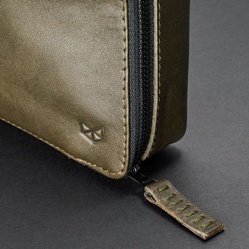 May include: A green leather zippered pouch with a small logo on the front. The zipper pull has a leather tab with the word "DISTIL" embossed on it.
