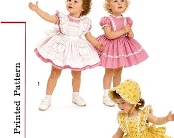 May include: A printed pattern labeled S1896 Size 2 featuring four dress designs. One dress is pink with a white pinafore, one is solid pink, one is yellow with a floral print and matching bonnet, and one is white with blue ribbon accents.