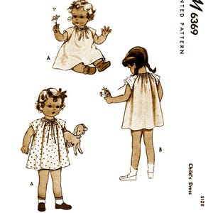 May include: A vintage sewing pattern for a child's dress. The pattern is for size 2 and includes two different styles. The pattern is printed on paper and has a brown background. The pattern number is M6369.